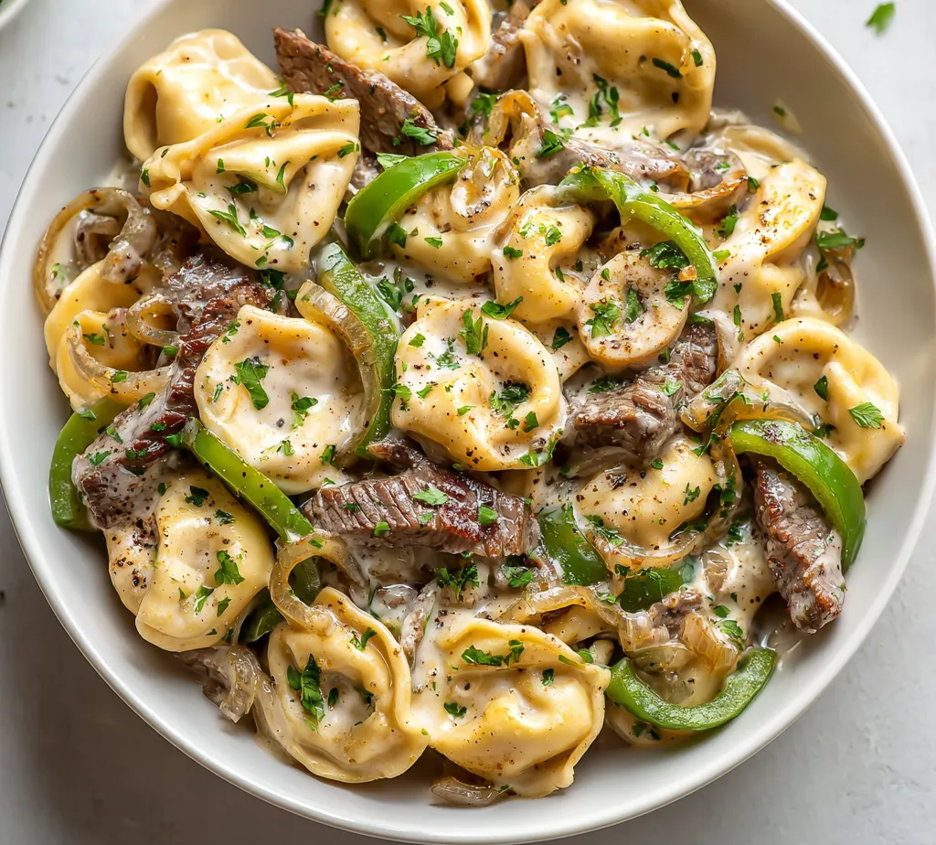 Cheesesteak Tortellini in Creamy Provolone Sauce is a delicious and comforting dish that expertly combines the rich, savory flavors of a classic cheesesteak with the tender texture of cheese tortellini. This culinary creation melds together perfectly cooked tortellini with premium ribeye steak, vibrant vegetables, and a sumptuous creamy sauce, resulting in an indulgent meal that's sure to satisfy. Whether you're looking for a quick weeknight dinner or a dish to impress guests at a gathering, this Cheesesteak Tortellini offers a delightful experience that is both satisfying and rich in flavor.